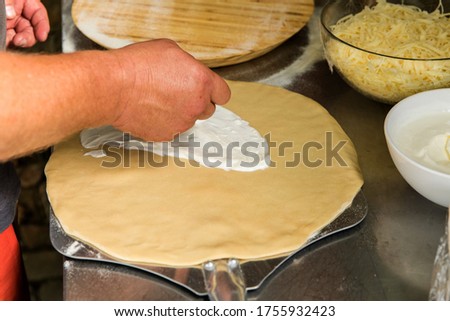Pizza dough. Process of preparing homemade pizza, a person rolls out the dough with his hands. Traditional Italian food.