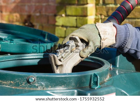 Closeup of man filling a bunded oil tank with domestic heating oil (kerosene) at a house in rural England, UK Royalty-Free Stock Photo #1755932552