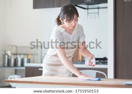 Asian woman disinfecting home dining table with spray