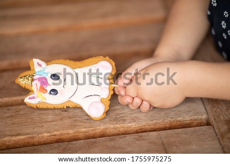 Gingerbread on a stick in children's hands. Unicorn Gingerbread. Image with selective focus.