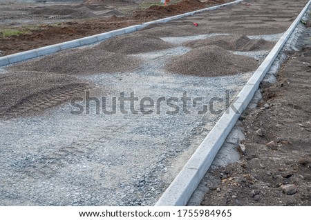 Construction of a road with curb, gravel bed and grit as a sub-structure of an asphalt road Royalty-Free Stock Photo #1755984965