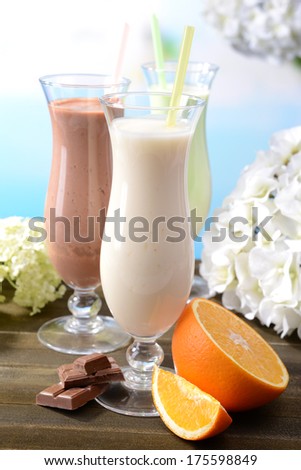 Milk shakes with fruits on table on light blue background