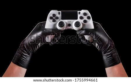 Hand in black gloves holding console gamepad isolated on black background with clipping path. Concept of medical and healthcare in video game industry