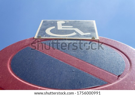 A low angle closeup shot of no parking sign with the exception for disabled people