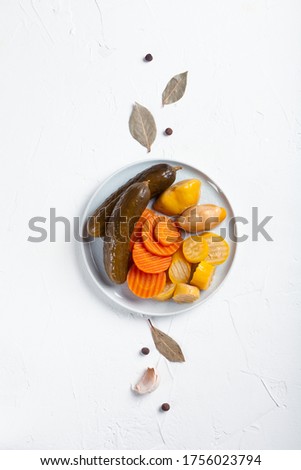 Fermented cucumbers, carrots and squash with ingredients on a white table