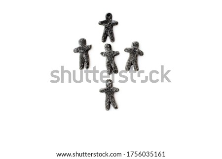 Black licorice jelly figurines of people are arranged in the form of a cross. Conceptual image.