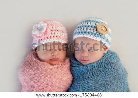 Five week old sleeping boy and girl fraternal twin newborn babies. They are wearing crocheted pink and blue striped hats. Royalty-Free Stock Photo #175604468