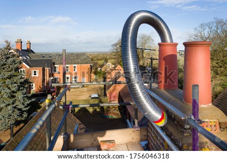 Installing a flexible steel flue liner into a chimney during a wood burning stove installation, UK Royalty-Free Stock Photo #1756046318