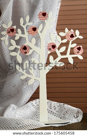 Decorative tree with decorative hearts, on wooden table on color fabric background