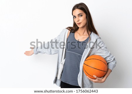 Young woman playing basketball isolated on white background extending hands to the side for inviting to come