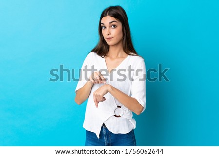 Young caucasian woman isolated on blue background making the gesture of being late