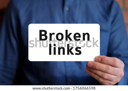 Broken links text on a white sign in the hand of a man in a blue shirt