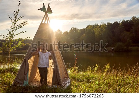 Girl at sunset in nature. Wigwam by the lake. New home in a hut. CHILDREN'S GAMES. High quality photo