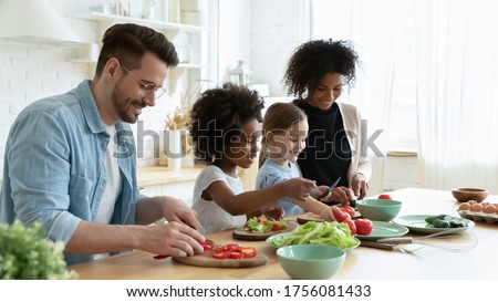 Full multinational family with cute daughters preparing dietary meal natural nutrition, cutting fresh vegetable for salad, parents caring for children health eat organic food, weekend activity at home Royalty-Free Stock Photo #1756081433