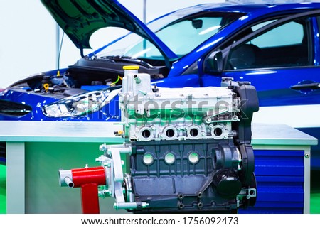 Auto repair shop. Engine got out of the car. Motor on the background of a blue car. Engine repair. Concept - collection of cars. Engine is fixed for repair. Concept - career in a car repairs shop