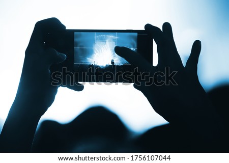 smartphone screen in the hand of a fan shooting video and memory photo at a concert of his favorite band. music festival atmosphere