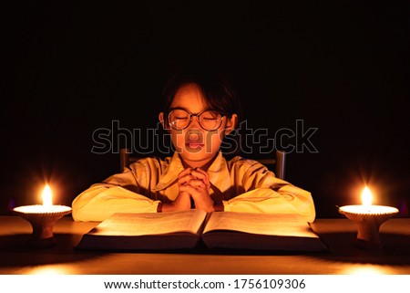 Cute little girl praying to the GOD with lighting candle at night time.