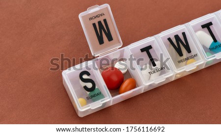 A weekly medicine dispenser opened for Monday, prescription pills and vitamins in a white pill box on terracotta background. Health care, vitamins and treatment concept. Horizontal shot Royalty-Free Stock Photo #1756116692