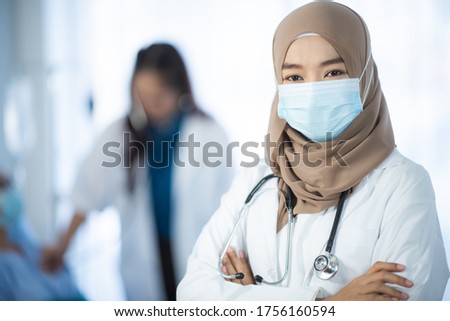 The beautiful Muslim woman doctor who wear hijab works at the hospital to take care of elderly patient. 