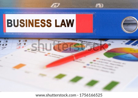 On the table are pie charts, a pen and a folder with the inscription - BUSINESS LAW. Business and finance concept.