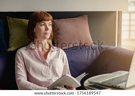 Portrait of young minded woman reading book before start working