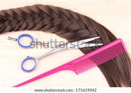 Long brown hair with comb and scissors on wooden background