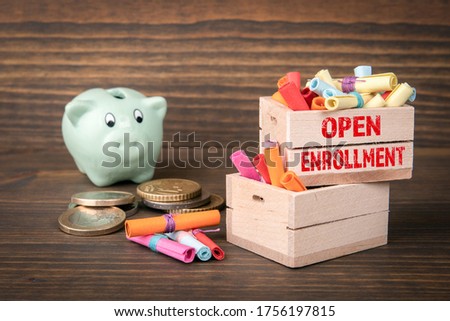 Open Enrollment concept. Colored papr scrolls in wooden boxes on dark wooden background. Full and almost empty containers