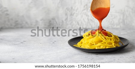 Italian tomato sauce pouring into fresh cooking spaghetti. Italian food concept large image for banner. Copy space