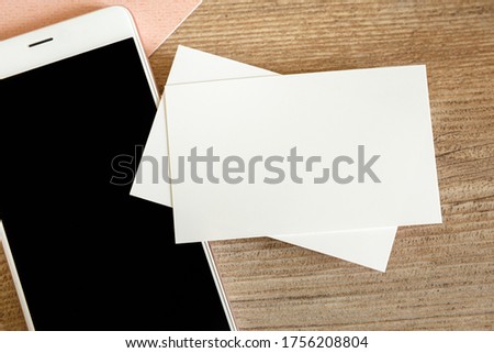 Mock up of blank business card and black smartphone screen on table