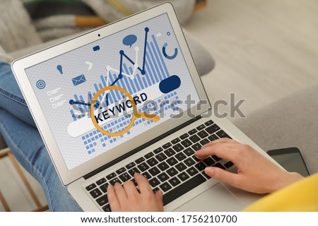 Woman with laptop searching for keyword at home, closeup Royalty-Free Stock Photo #1756210700