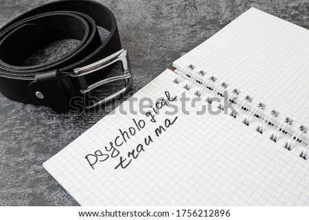 notebook with psychological trauma inscription and dark leather male belt as ptsd symbol on black background, ptsd concept. Post Traumatic Stress Disorder concept. 27 june ptsd day