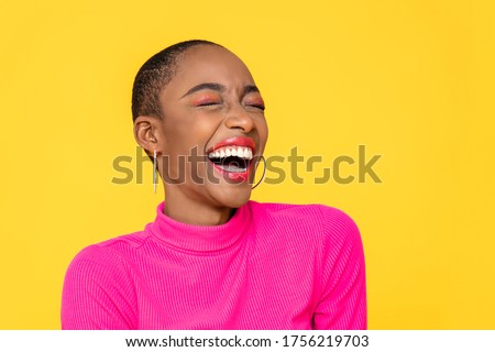 Happy optimistic African American woman in colorful pink clothes laughing isolated on yellow background Royalty-Free Stock Photo #1756219703