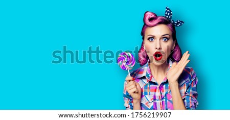Purple head excited surprised woman with lollipop. Pinup girl with opened mouth. Beauty model at retro fashion and vintage concept. Aqua blue color background with copy space for some advertise text. 