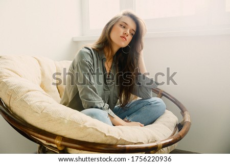 people, technology and the concept of leisure-a happy European young woman sitting on a sofa with headphones and listening to music at home