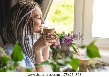 A cute young woman is enjoying an aromatic coffee on a sunny summer morning. Concept of a dreamy mood, a cozy atmosphere and a pleasant start to the day.