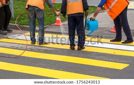 road workers create a new pedestrian crossing spray and fix white paint on the road