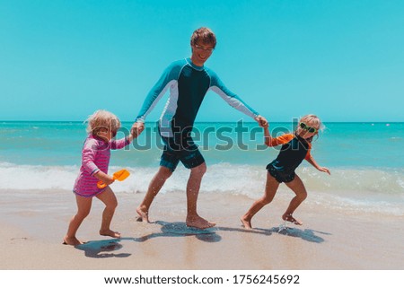 father with kids run at beach, family have fun at sea