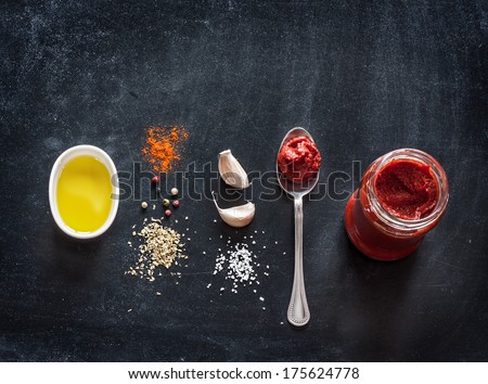 Pizza topping sauce ingredients or recipe on black background. Tomato puree, olive oil, garlic, oregano, salt and pepper from above - cooking food. Background with free text space.