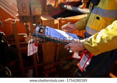 Site safety auditor supervisor verifying name of co workers on isolation lock permit board ensure are locking on and working on correct equipment prior starting each shift   Royalty-Free Stock Photo #1756280189