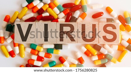 Wooden blocks with VIRUS lettering and pile of pills on white background