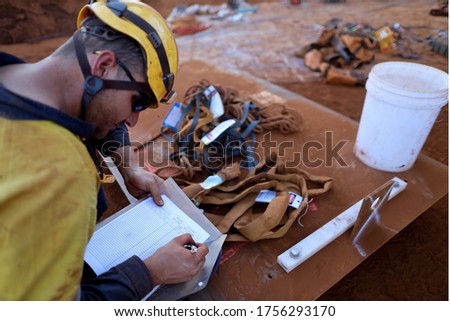 Defocused safety workplace trained competent safety auditor engineer wearing yellow safety helmet inspecting writing on paper crane lifting safety sling checking list prior used   Royalty-Free Stock Photo #1756293170