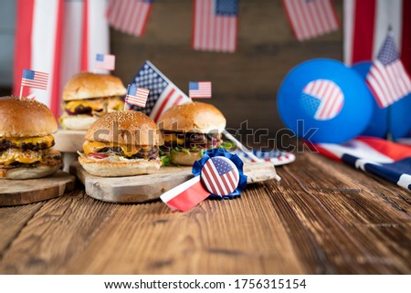 Tasty burgers on rustic wooden table. American decorations. 4th of July celebration concept.