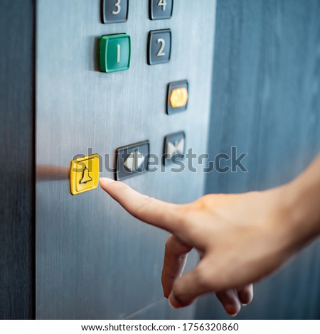 Male forefinger pressing on emergency stop and alarm button in elevator (lift). Mechanical engineering concept