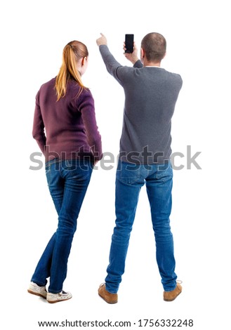 Back view of couple in sweater with mobile phone. beautiful friendly girl and guy together. Rear view people collection. backside view of person. Isolated over white background.