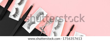 Various tools for eyelash extensions on a trendy pastel pink and black background. Banner. Concept. Eyelash curler, tweezers. Makeup accessories. Cosmetics. Fake eye lashes. Place for text. Top view.