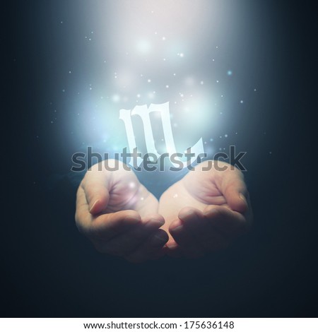 Horoscope Scorpio sign, female hands opening to light and holding zodiac symbol