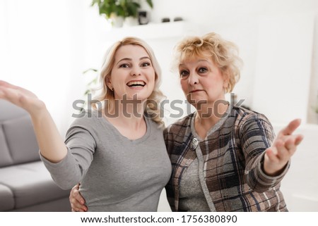Self portrait of pretty charming positive funky mother and daughter shooting selfie on front camera having video-call sitting in modern white living room enjoying meeting free time