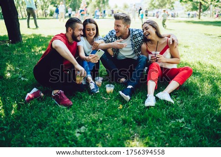 Group of joyful male and female vloggers shotting selfie video for communicate with social followers during weekend in public park,happy hipster guys reading funny news on website during double date