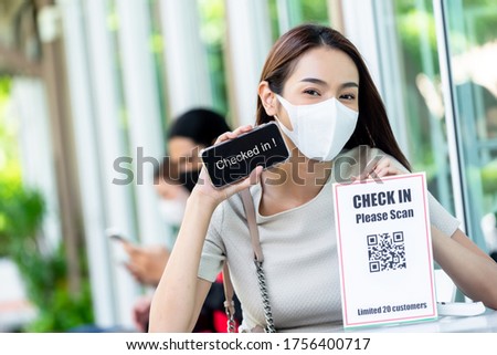 Cute teenage woman show smartphone after checked in into restaurant for application record track and trace customer during covid pandemic