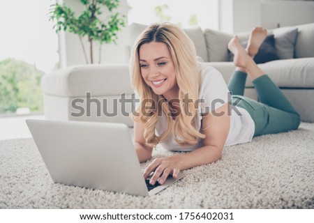 Closeup photo of domestic house wife lady relaxing lying comfy floor near couch browsing notebook remote work freelancer stay home good mood quarantine time living room indoors
